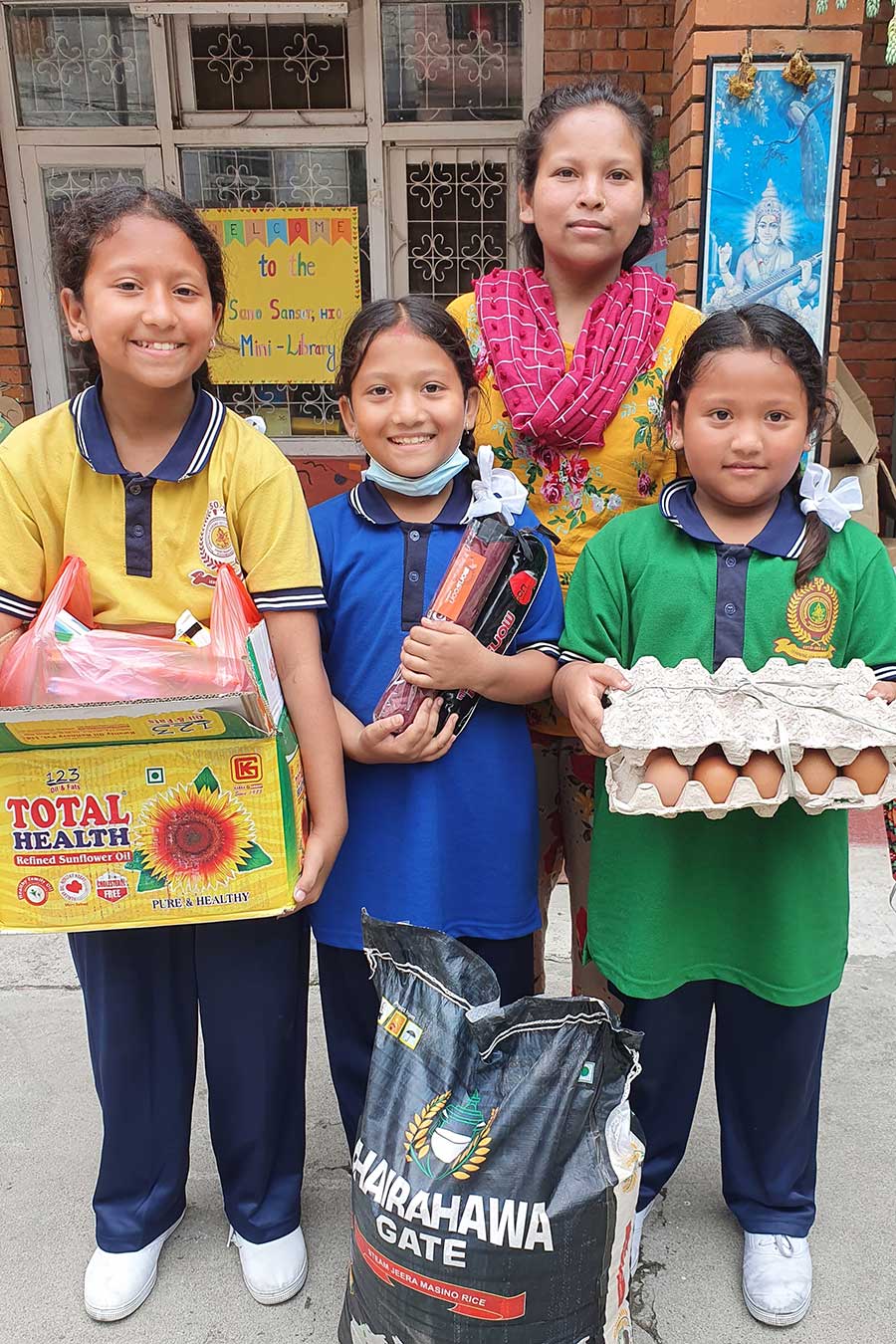 A mother and three children holding a month's worth of food